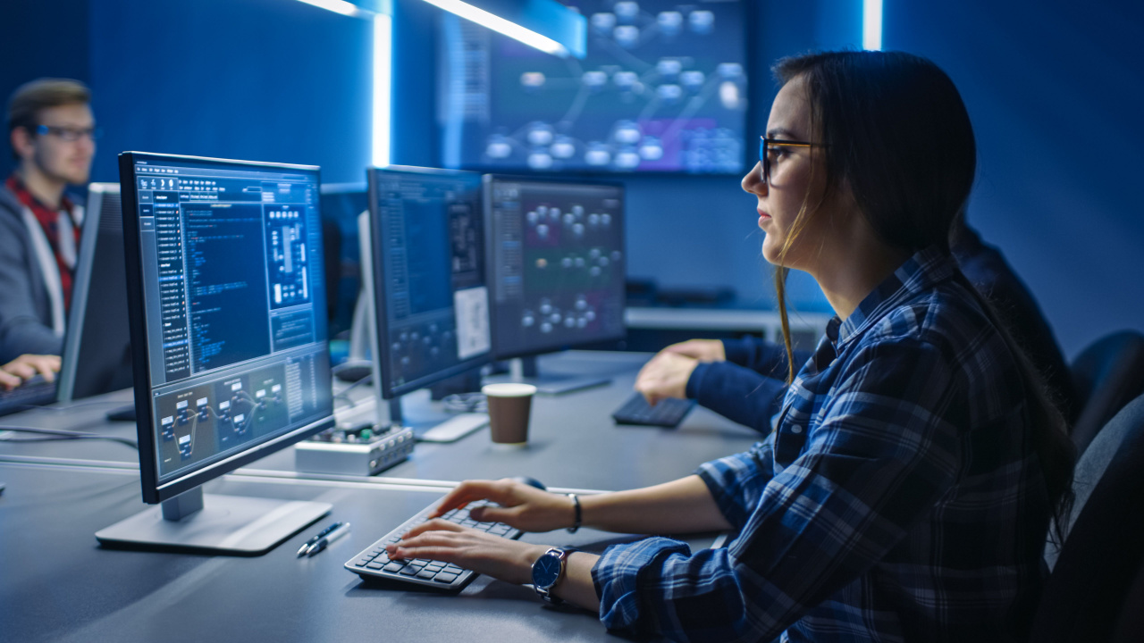 A female security analyst sitting in front of a computer screen