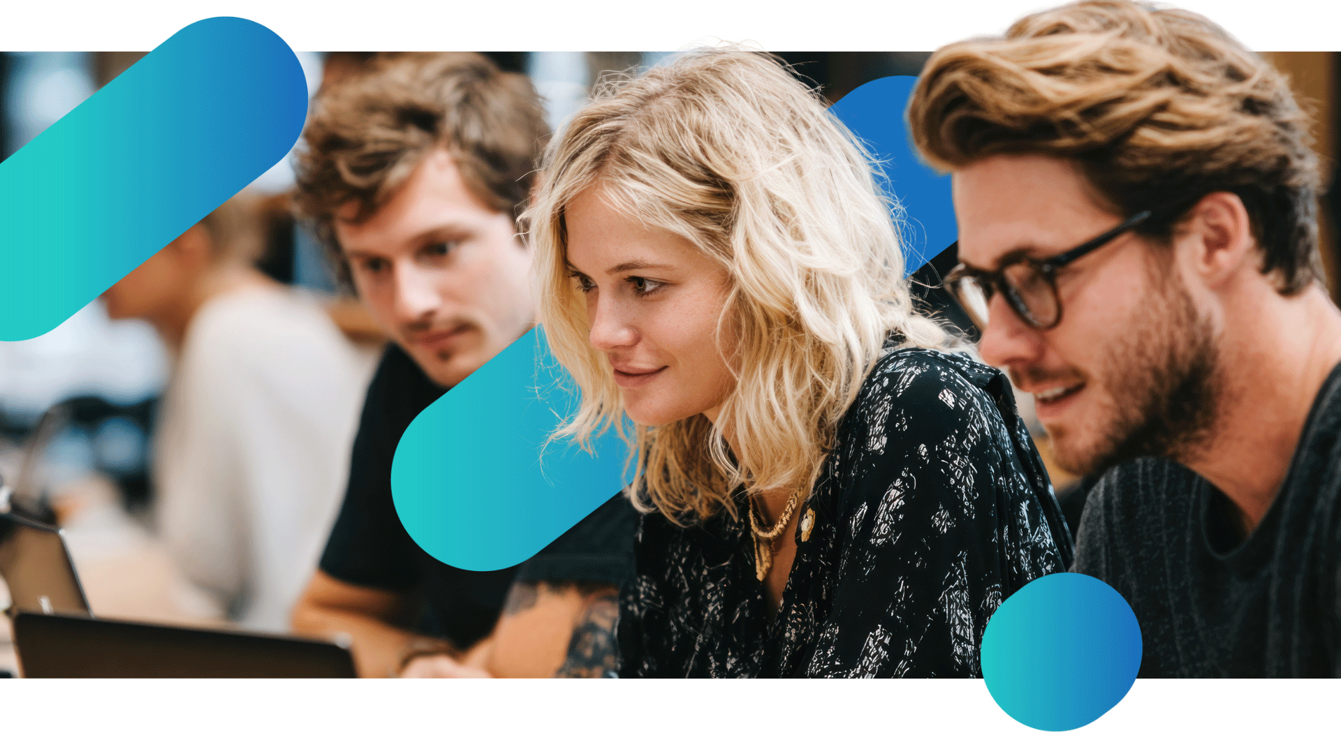 Three people at a desk in an office looking at a computer